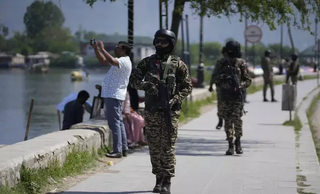 Indian soldiers guard as a tourist take picture with his cell phone on the banks of Dal Lake in Srinagar, Indian controlled Kashmir, Thursday, April 24, 2025. (AP Photo/Mukhtar Khan)