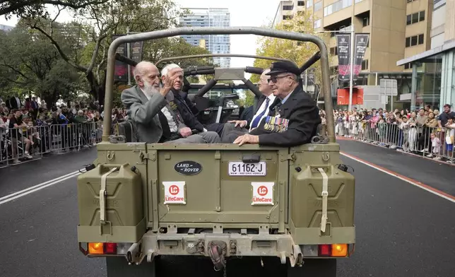 Veterans ride in the back of an army truck past thousands of people lining the street to pay tribute to their war dead during the Anzac Day parade in Sydney, Australia, Friday, April 25, 2025. (AP Photo/Rick Rycroft)