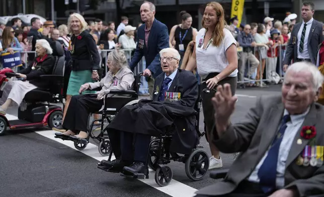 Participants are assisted as they march past thousands of people lining the street to pay tribute to their war dead during the Anzac Day parade in Sydney, Australia, Friday, April 25, 2025. (AP Photo/Rick Rycroft)