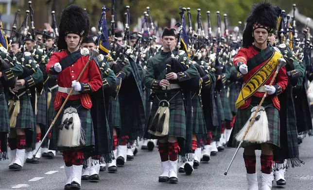A pipe band marches past thousands of people lining the street to pay tribute to their war dead during the Anzac Day parade in Sydney, Australia, Friday, April 25, 2025. (AP Photo/Rick Rycroft)