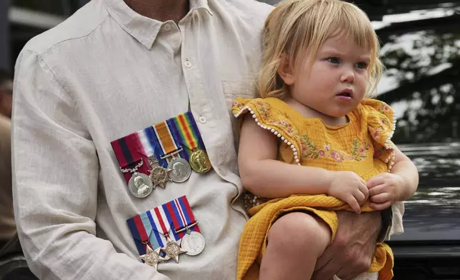 A father holds his child as during the Anzac Day commemorations in Nelson Bay, Australia, Friday, April 25, 2025. (AP Photo/Mark Baker)