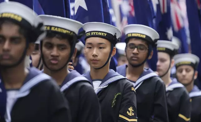 Cadets carrying Australian flags march past thousands of people lining the street to pay tribute to their war dead during the Anzac Day parade in Sydney, Australia, Friday, April 25, 2025. (AP Photo/Rick Rycroft)