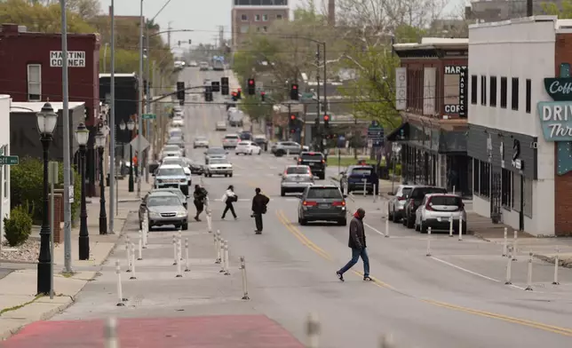 People cross 31st Street in Kansas City, Mo., where the city implemented a "road diet" reducing the street from four lanes to two in an effort to reduce speeding and accidents, Thursday, April 17, 2025. (AP Photo/Charlie Riedel)