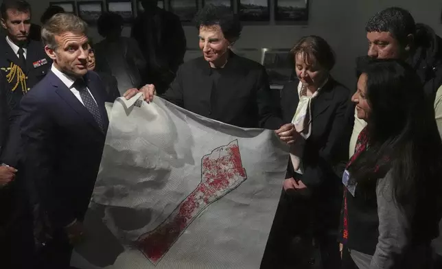 French President Emmanuel Macron, left, and IMA director Jack Lang, center, hold a map of Palestine as they visit the exhibition "Treasures rescued from Gaza" Monday, April 14, 2025 at the Arab World Institute (IMA) in Paris. (AP Photo/Michel Euler, Pool)