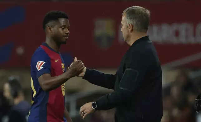 Barcelona's head coach Hansi Flick, right, greets Barcelona's Ansu Fati after he is substituted by Barcelona's Raphinha during a Spanish La Liga soccer match between Barcelona and Mallorca at the Lluis Companys Olympic stadium in Barcelona, Spain, Tuesday, April 22, 2025. (AP Photo/Joan Monfort)