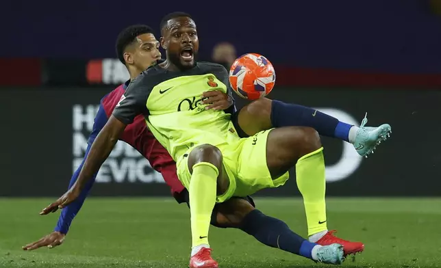 Mallorca's Cyle Larin, foreground, is challenged by Barcelona's Ronald Araujo during a Spanish La Liga soccer match between Barcelona and Mallorca at the Lluis Companys Olympic stadium in Barcelona, Spain, Tuesday, April 22, 2025. (AP Photo/Joan Monfort)