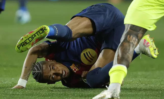 Barcelona's Raphinha falls to the ground after a challenge with Mallorca's Antonio Sanchez during a Spanish La Liga soccer match between Barcelona and Mallorca at the Lluis Companys Olympic stadium in Barcelona, Spain, Tuesday, April 22, 2025. (AP Photo/Joan Monfort)