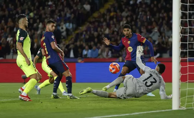 Barcelona's Ronald Araujo, second right, attempts a shot at goal in front of Mallorca's goalkeeper Leo Roman during a Spanish La Liga soccer match between Barcelona and Mallorca at the Lluis Companys Olympic stadium in Barcelona, Spain, Tuesday, April 22, 2025. (AP Photo/Joan Monfort)