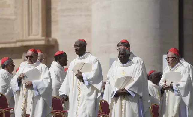 Cardinals, including Chibly Langlois, center left, and Peter Kodwo Appiah Turkson, center right, arrive for a mass presided by Vatican Secretary of State, Cardinal Pietro Parolin, on the second of nine days of mourning for late Pope Francis, in St. Peter’s Square, at the Vatican, Sunday, April 27, 2025. (AP Photo/Gregorio Borgia)