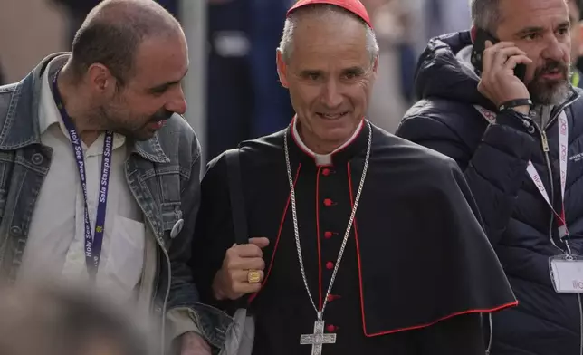 Cardinal Jean-Paul Vesco, center, is approached by a reporter as he arrives for a college of cardinals' meeting, at the Vatican, Friday, April 25, 2025. (AP Photo/Gregorio Borgia)