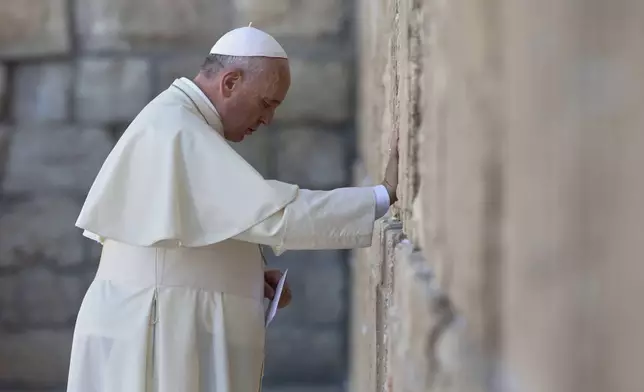 FILE - Pope Francis prays as he holds an envelope before placing it in on of the cracks between the stones of the Western Wall, the holiest place where Jews can pray, in the old city of Jerusalem, Israel, Monday, May 26, 2014. (AP Photo/Andrew Medichini, Pool, file)