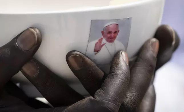 A priest holds a sacrament bowl showing a photograph of Pope Francis at a Holy Mass at the John Garang Mausoleum in Juba, South Sudan Sunday, Feb. 5, 2023. (AP Photo/Ben Curtis, File)