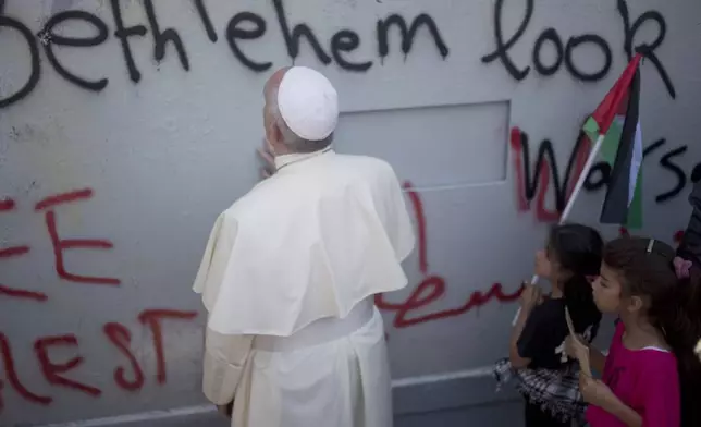 FILE - Pope Francis prays at Israel's separation barrier on his way to a mass in Manger Square next to the Church of the Nativity, traditionally believed to be the birthplace of Jesus Christ in the West Bank city of Bethlehem on Sunday, May 25, 2014. (AP Photo/Ariel Schalit, file)
