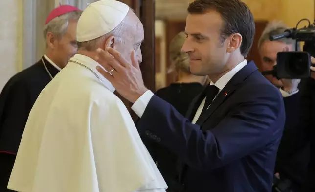 FILE - French President Emmanuel Macron, right, shakes hands with and goes to hug Pope Francis at the end of their private audience, at the Vatican, Tuesday, June 26, 2018. (Alessandra Tarantino/Pool, file)
