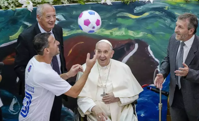 Pope Francis and Scholas Occurrentes' President Jose Maria Del Corral, left, look at Newell's Old Boys captain, Argentine midfielder Maxi Rodriguez juggling a soccer ball at the launch of the 'Scholas Occurrentes' (Latin for, schools of meeting) international educational movement at the pontifical Urbaniana University in Rome, Thursday, May 19, 2022. (AP Photo/Andrew Medichini)