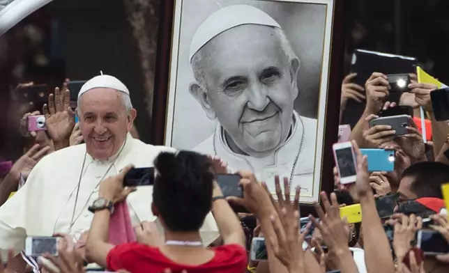 FILE - Pope Francis passes a portrait of himself as he arrives to meet youths in Santo Tomas University in Manila, Philippines, Sunday, Jan. 18, 2015. (AP Photo/Alessandra Tarantino, File)