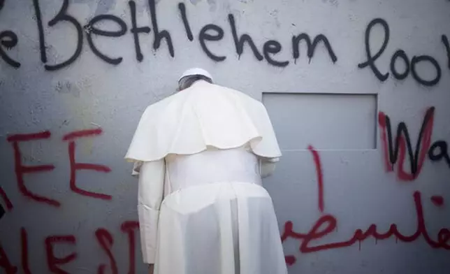 FILE - Pope Francis prays at Israel's separation barrier on his way to a mass in Manger Square next to the Church of the Nativity, in the West Bank city of Bethlehem, Sunday, May 25, 2014. (AP Photo/Ariel Schalit, file)