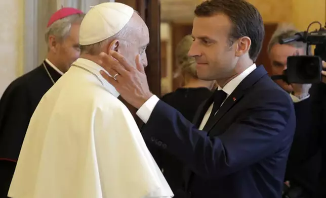FILE - French President Emmanuel Macron, right, shakes hands with and goes to hug Pope Francis at the end of their private audience, at the Vatican, Tuesday, June 26, 2018. (Alessandra Tarantino/Pool Photo via AP, File)