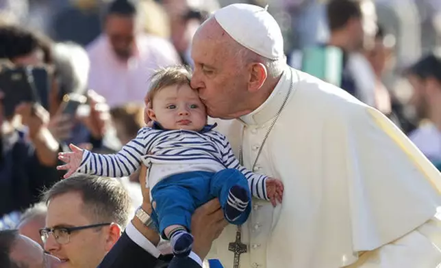 FILE - Pope Francis kisses a baby as he arrives for his weekly general audience, in St. Peter's Square, at the Vatican, Wednesday, Oct. 23, 2019. (AP Photo/Andrew Medichini, file)