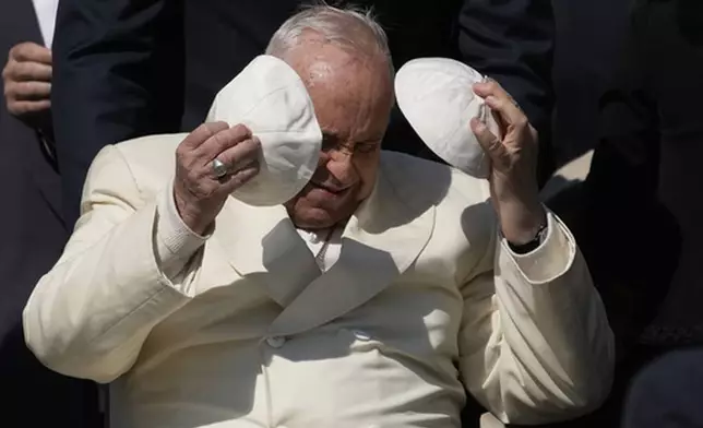 FILE - Pope Francis exchanges his skull cap with one presented by a participant in the weekly general audience in St. Peter's Square, at the Vatican, Wednesday, April 19, 2023. (AP Photo/Alessandra Tarantino, File)