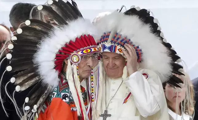 FILE - Pope Francis puts on an indigenous headdress during a meeting with Indigenous communities, including First Nations, Metis and Inuit, at Our Lady of Seven Sorrows Catholic Church in Maskwacis, near Edmonton, Canada, Monday, July 25, 2022. (AP Photo/Gregorio Borgia, File)