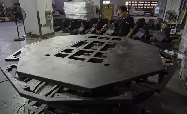 A worker labors on a platform for a virtual reality game machine produced at the factory for Zhuoyuan Tech Co., Ltd in Panyu district of Guangzhou city in southern China's Guangdong province on Wednesday, April 16, 2025. (AP Photo/Ng Han Guan)