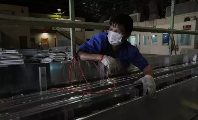 A worker holds together aluminum panels at a factory of Kam Pin Industrial (HK) Ltd, in Dongguan city in southern China's Guangdong province on Thursday, April 17, 2025. (AP Photo/Ng Han Guan)