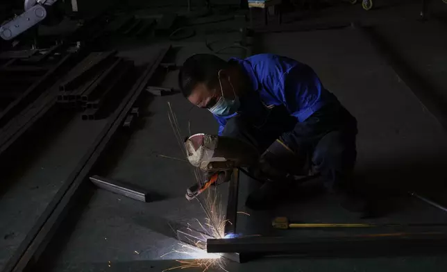 A worker welds together metal parts at the factory of Kam Pin Industrial (HK) Ltd, manufacturer of coated aluminum panels in Dongguan city in southern China's Guangdong province on Thursday, April 17, 2025. (AP Photo/Ng Han Guan)