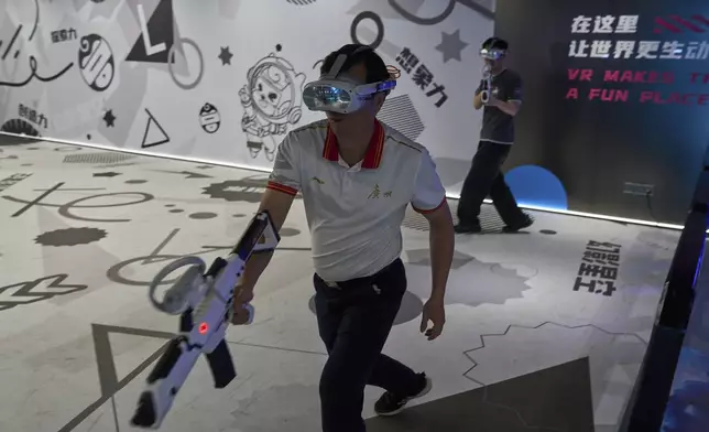 Visitors try out a virtual reality game at the experience center of Zhuoyuan Tech Co., Ltd in Panyu district of Guangzhou city in southern China's Guangdong province on Wednesday, April 16, 2025. (AP Photo/Ng Han Guan)