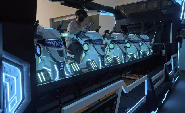 A worker tests out virtual reality rides at the factory of Zhuoyuan Tech Co., Ltd in Panyu district of Guangzhou city in southern China's Guangdong province on Wednesday, April 16, 2025. (AP Photo/Ng Han Guan)