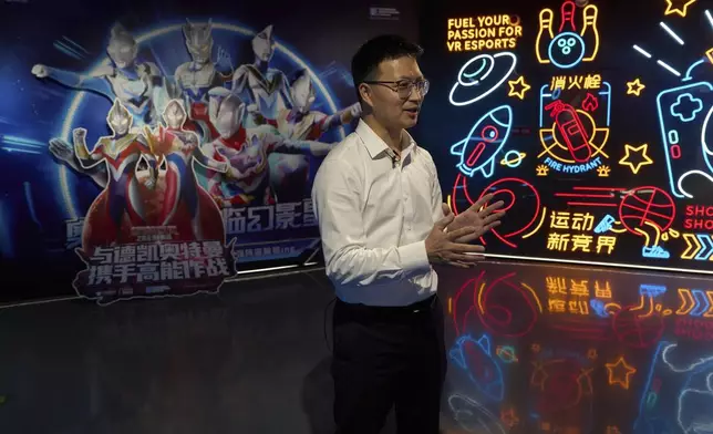 Zou Huajian, overseas sales manager of Zhuoyuan Tech Co., Ltd talks about the Virtual Reality products at the experience center in Panyu district of Guangzhou city in southern China's Guangdong province on Wednesday, April 16, 2025. (AP Photo/Ng Han Guan)