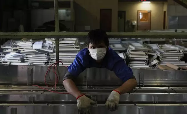 A worker holds together aluminum panels at a factory of Kam Pin Industrial (HK) Ltd, in Dongguan city in southern China's Guangdong province on Thursday, April 17, 2025. (AP Photo/Ng Han Guan)