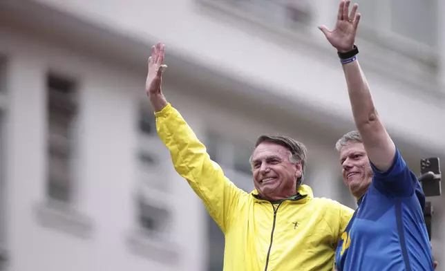 Sao Paulo Governor Tarcisio de Freitas, right, and former President Jair Bolsonaro wave to supporters during a demonstration demanding amnesty for those arrested for 2023's alleged coup attempt, in Sao Paulo, Sunday, April 6, 2025. (AP Photo/Ettore Chiereguini)