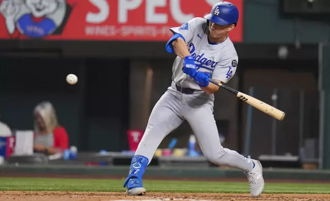 Los Angeles Dodgers' Tommy Edman swings at a pitch while hitting a single against the Texas Rangers during the sixth inning of a baseball game Friday, April 18, 2025, in Arlington, Texas. (AP Photo/Julio Cortez)