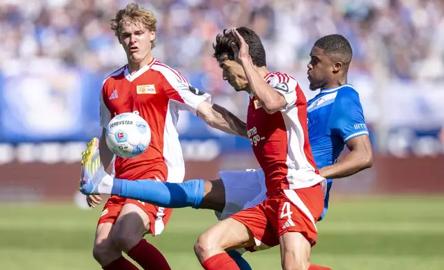 Berlin's Tom Rothe, left, and Diogo Leite, center, challenge for the ball with Bochum's Myron Boadu, right, during the German Bundesliga soccer match between VfL Bochum and 1. FC Union Berlin in Bochum, Germany, Sunday, April 27, 2025. (David Inderlied/dpa via AP)