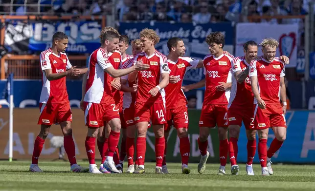 Berlin's players celebrate the opening goal scored by Benedict Hollerbach, right, during the German Bundesliga soccer match between VfL Bochum and 1. FC Union Berlin in Bochum, Germany, Sunday, April 27, 2025. (David Inderlied/dpa via AP)