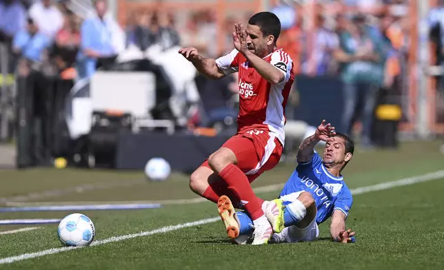 Berlin's Rani Khedira, left, and Bochum's Cristian Gamboa, right, challenge for the ball during the German Bundesliga soccer match between VfL Bochum and 1. FC Union Berlin in Bochum, Germany, Sunday, April 27, 2025. (David Inderlied/dpa via AP)