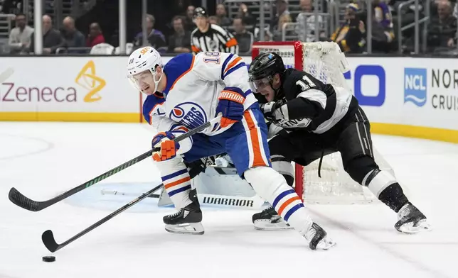 Edmonton Oilers left wing Zach Hyman, left, moves the puck as Los Angeles Kings center Anze Kopitar puts pressure on him during the first period in Game 2 of an NHL hockey first-round playoff series Wednesday, April 23, 2025, in Los Angeles. (AP Photo/Mark J. Terrill)