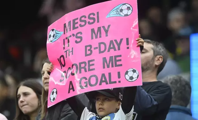 A fan holds a sign during the first half of an MLS soccer match between the Columbus Crew and Inter Miami, Saturday, April 19, 2025, in Cleveland, Ohio. (AP Photo/David Richard)