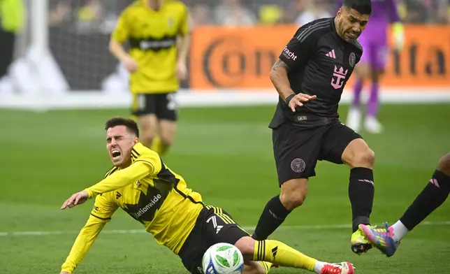 Columbus Crew midfielder Dylan Chambost, left, falls while defended by Inter Miami forward Luis Suarez, right, during the first half of an MLS soccer match Saturday, April 19, 2025, in Cleveland, Ohio. (AP Photo/David Richard)