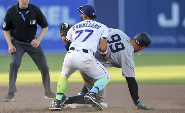 Tampa Bay Rays' José Caballero (77) tags out New York Yankees' Aaron Judge (99) on a steal-attempt during the ninth inning of a baseball game Saturday, April 19, 2025, in Tampa, Fla. (AP Photo/Mike Carlson)