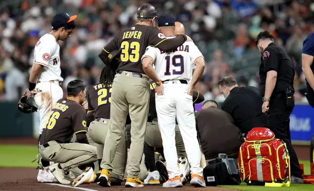 San Diego Padres third base coach Tim Leiper (33) hugs Houston Astros manager Joe Espada (19) after Padres' Luis Arraez lies on the ground after a collision with with Astros second baseman Mauricio Dubon at first base rduring the first inning of a baseball game Sunday, April 20, 2025, in Houston. (AP Photo/Karen Warren)