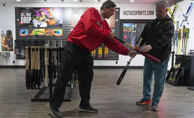 Customers Ed Costantini, left, and Jack Bradley compare a conventional bat with a torpedo baseball bat at Victus Sports in King of Prussia, Pa., Wednesday, April 2, 2025. (AP Photo/Matt Rourke)