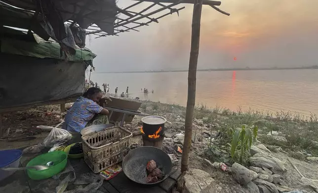 A woman cooks while local residents take shower at a jetty in Mandalay, Myanmar, Tuesday, April 1, 2025. (AP Photo)