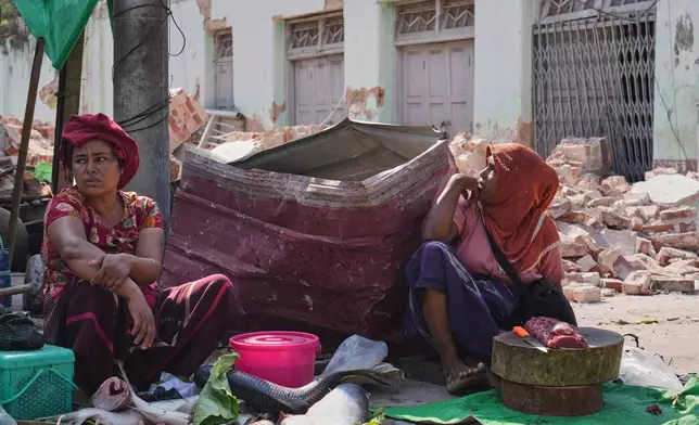 A fish vendor awaits customers at a local bazaar next to damaged buildings following Friday's earthquake in Naypyitaw, Myanmar, Tuesday, April 1, 2025. (AP Photo)
