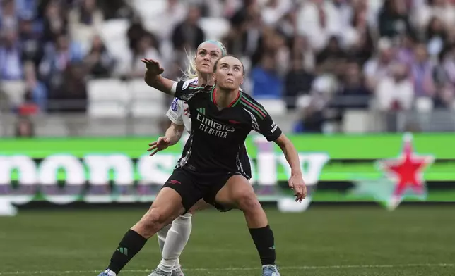 Arsenal's Caitlin Foord and Lyon's Ellie Carpenter, background, eye the ball during the women's Champions League semifinals, second leg, soccer match between Olympique Lyonnais and Arsenal at OL Stadium in Decines, outside Lyon, France, Sunday, April 27, 2025. (AP Photo/Thibault Camus)