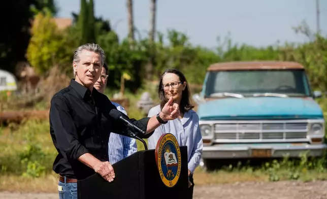 California Gov. Gavin Newsom discusses President Donald Trump's tariffs, as almond farmer Christine Gemperle, listens, during a press conference on Wednesday, April 16, 2025, at an almond farm in Ceres, Calif. (AP Photo/Noah Berger)
