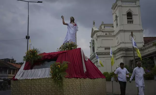 Sri Lankan Catholics walk past a statue of Jesus Christ outside St. Anthony's Church during a ceremony marking the sixth anniversary of the 2019 Easter Sunday attacks in Colombo, Sri Lanka, Monday, April 21, 2025. (AP Photo/Eranga Jayawardena)