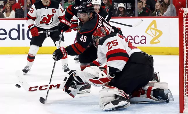 Carolina Hurricanes' Jordan Martinook (48) controls the puck in front of New Jersey Devils goaltender Jacob Markstrom (25) during the second period of Game 1 of an NHL hockey Stanley Cup first-round playoff series in Raleigh, N.C., Sunday, April 20, 2025. (AP Photo/Karl DeBlaker)