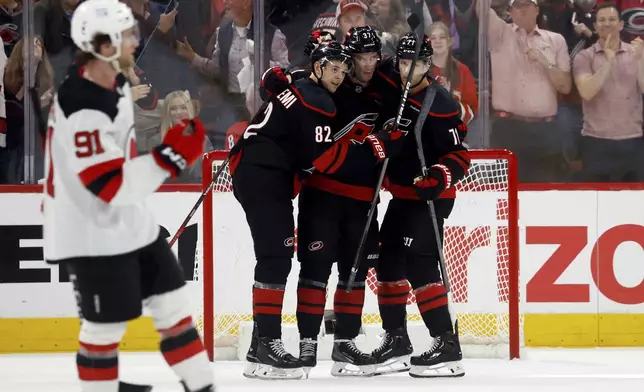 Carolina Hurricanes' Andrei Svechnikov, center, celebrates his goal with Jesperi Kotkaniemi (82) and Taylor Hall (71) during the third period of Game 1 of an NHL hockey Stanley Cup first-round playoff series against the New Jersey Devils in Raleigh, N.C., Sunday, April 20, 2025. (AP Photo/Karl DeBlaker)